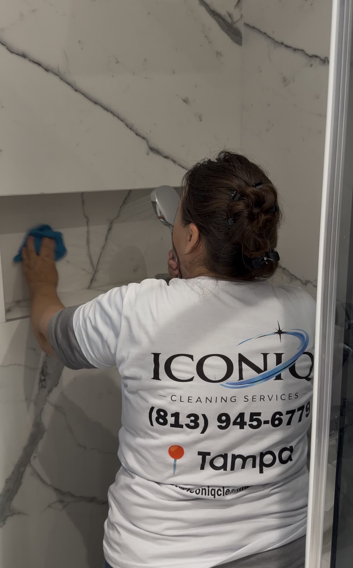 Iconiq cleaner wiping down a marble shower in a Tampa home