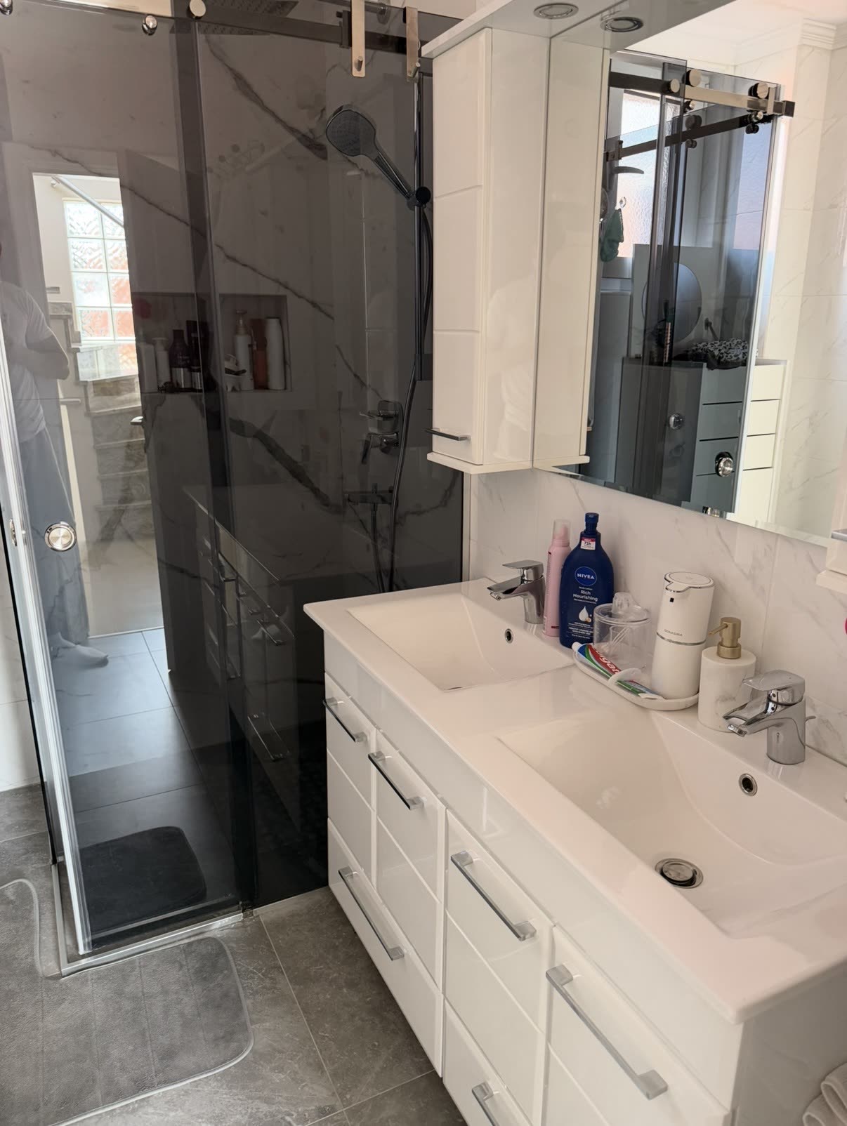 Polished marble walk-in shower and vanity after an Iconiq clean